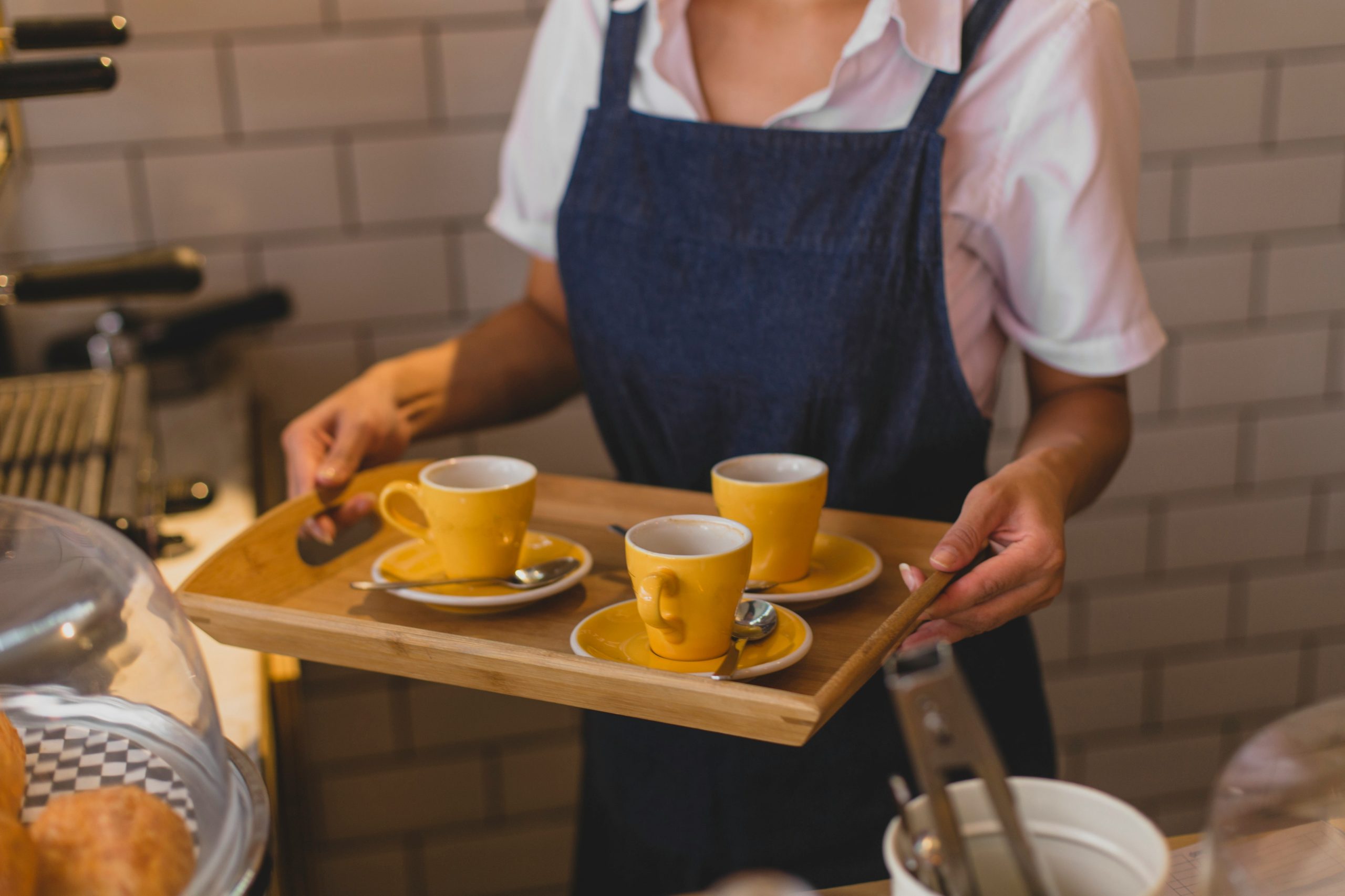 Photo of a waiter holding the tray with 3 cups